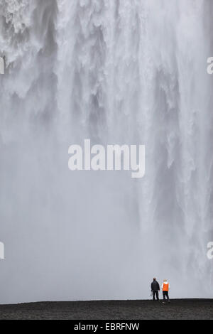 zwei Menschen stehen vor Skogafoss Wasserfall, Island Stockfoto