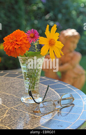 Vase mit Blumen und Gläser im Garten Stockfoto