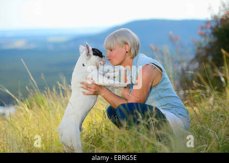 Französische Bulldogge (Canis Lupus F. Familiaris), sahen einander Frau und Hund umarmt auf einer Wiese, Deutschland Stockfoto