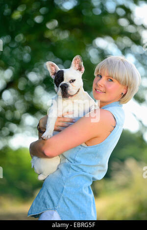 Französische Bulldogge (Canis Lupus F. Familiaris), junge Frau hält eine französische Bulldogge auf dem Arm, Deutschland Stockfoto