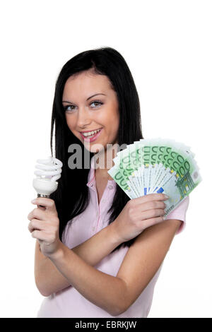 Frau mit Energiesparlampe und. Energiesparende Lampe und Währung Stockfoto