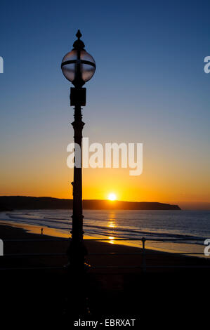 Eine Laterne auf der West Pier Silhoutted von der Sonne wie es geht hinter Whitbys Ness, Whitby, North Yorkshire. Mai. Stockfoto