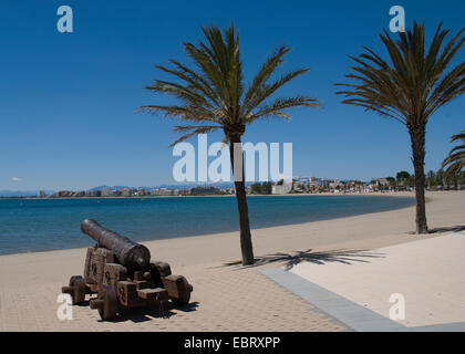 Blick auf Roses an der katalanischen Küste Spaniens mit alten Kanonen im Vordergrund vor blauem Himmel und leerem Strand an einem schönen sonnigen, aber heißen Tag Stockfoto