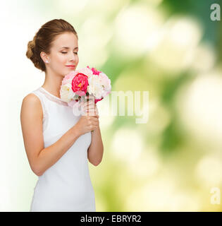 lächelnde Frau in weißem Kleid mit Rosenstrauß Stockfoto