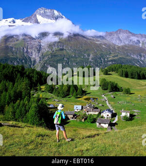 weibliche Wanderer Blick auf kleine Dorf von Le Monal und Mont Pourri, Frankreich, Savoyen, Nationalparks Vanoise, Sainte-Foy-Tarentaise Stockfoto
