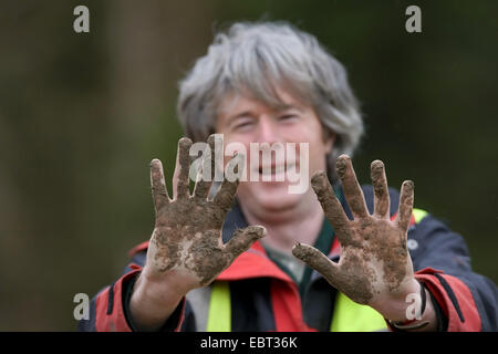 Mann mit schlammigen Händen während Baumpflanzaktion Sitzung, Großbritannien, Schottland Stockfoto