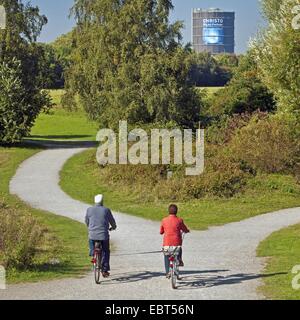 zwei Radfahrer in den Baum und Strauch Garten Ripshorst, Gasometer Oberhausen im Hintergrund, Oberhausen, Ruhrgebiet, Nordrhein-Westfalen, Deutschland Stockfoto