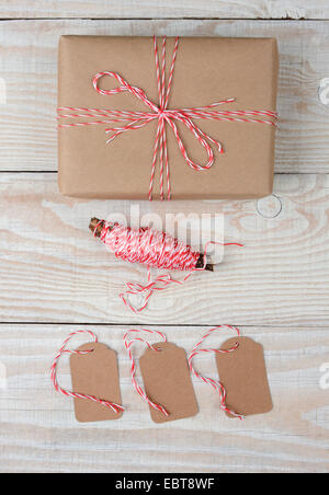 Hohen Winkel Schuss ein Weihnachtspaket in braunen Papier eingewickelt und mit roten und weißen Schnur gebunden. Drei leere Tags und spo Stockfoto