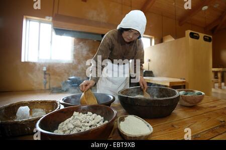 Kim Eul-Jung, 84, der einzige Meister zu machen, die traditionelle Schnaps Omegisul arbeitsintensiver Prozess im Seongeup Folk Village zeigt 29. November 2014 in Seogwipo-Si, Insel Jeju, Südkorea.  Der Prozess beinhaltet Kochen und Zerkleinerung eine Maische hergestellt aus gedämpfter Hirse Kuchen, Malz und Wasser, das in ein alkoholisches Getränk fermentiert wird. Stockfoto