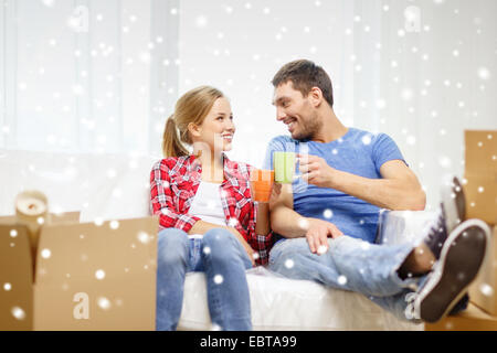 lächelnde paar trinken Tee oder Kaffee im neuen Zuhause Stockfoto