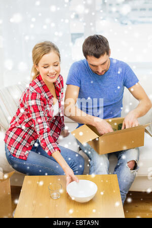lächelnde paar Eröffnung Karton mit Geschirr Stockfoto