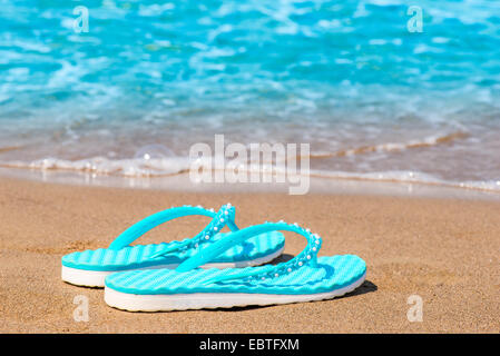 Türkis flip Flops an einer sandigen Küste aufgegeben Stockfoto