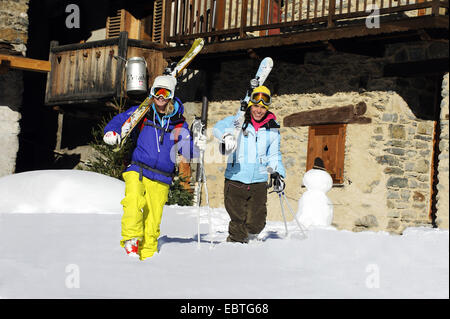 zwei Frauen mit Skiausrüstung zu Fuß durch Bergdorf, Frankreich, Savoyen, Sainte-Foy-Tarentaise Stockfoto