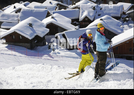 zwei Skifahrer stehen vor Schnee bedeckten Bergdorf, Savoie, Frankreich, Sainte-Foy-Tarentaise Stockfoto