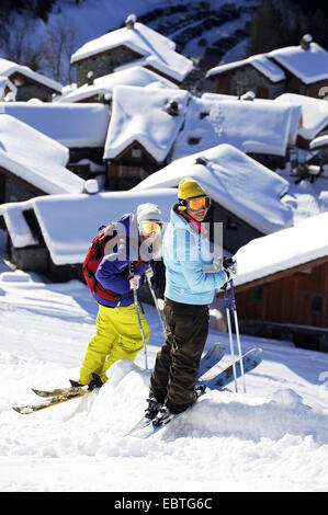 zwei Skifahrer stehen vor Schnee bedeckten Bergdorf, Savoie, Frankreich, Sainte-Foy-Tarentaise Stockfoto