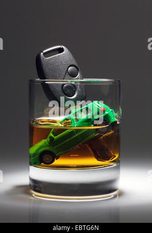 Spielzeugauto und Autoschlüssel Untergang in einem Glas Alkohol Stockfoto