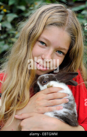 Hauskaninchen (Oryctolagus Cuniculus F. Domestica), 11 Jahre alten Mädchen, eine niedlichen Kaninchen kuscheln Stockfoto