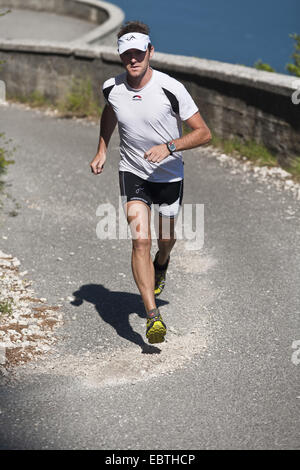 Mann Joggen auf einem asphaltierten Weg in den Bergen hoch über dem Gardasee, Italien Stockfoto