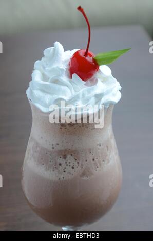 Schokoladenmilchshake mit Milchschaumcreme und Kirsche auf dem Tob Stockfoto