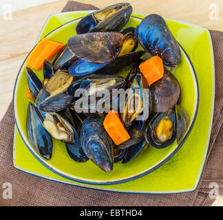 Gekochte Muscheln mit Gemüse in einer Keramikschale. Stockfoto