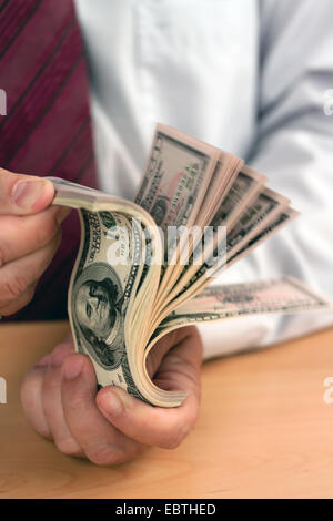 Business-Mann ein Bündel Dollarnoten durchblättern Stockfoto