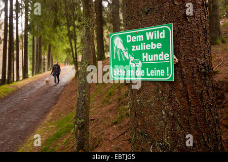 junge Frau nehmen den Hund für einen Spaziergang neben einem Schild "Hunde an der Leine", Deutschland, Rheinland-Pfalz Stockfoto