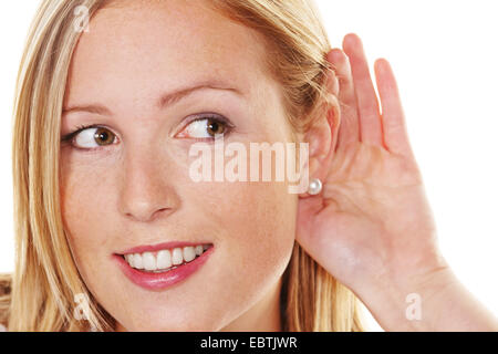 junge Frau an der Hand hinter dem Ohr für Lauschangriffe Stockfoto
