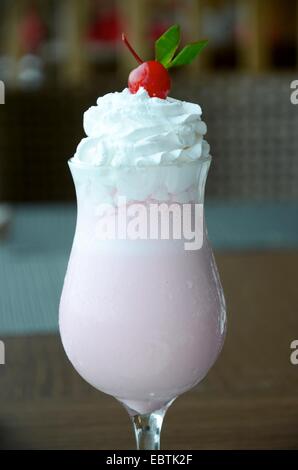 Köstlicher Erdbeermilchshake mit Schlagsahne und Kirsche Stockfoto