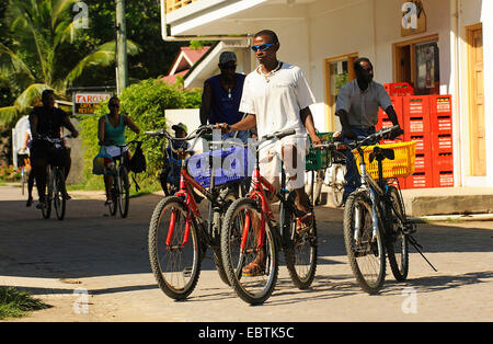 junger Mann Radfahren und den Transport in jeder Hand ein anderes Motorrad, Seychellen Stockfoto