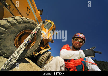 Freeride-Skifahrer sitzen vor einem Bulldozer in einem Steinbruch Stockfoto