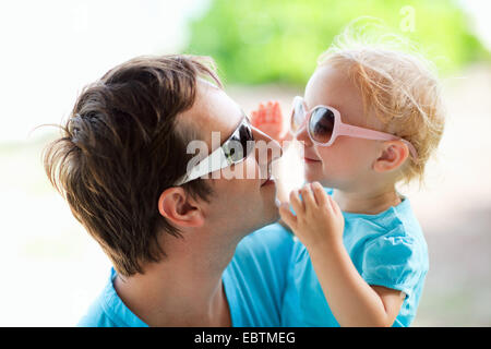 junger Vater und der kleinen Tochter am Arm glücklich Blick in die Augen durch ihre Sonnenbrille Stockfoto