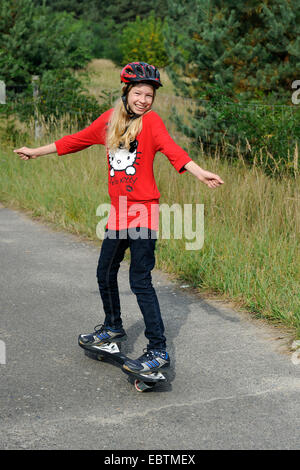 elf Jahre altes Mädchen auf einem casterboard Stockfoto