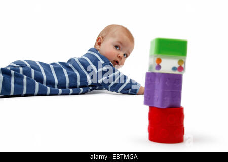 neugierig Baby Strampler auf dem Boden liegend und auf Baby-Spielzeug Stockfoto