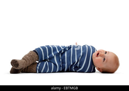 kleiner Junge in Strampler auf dem Boden liegend und umdrehen Stockfoto