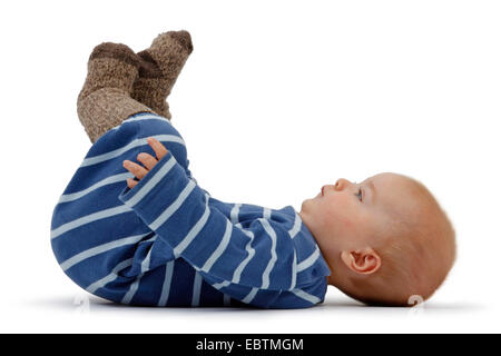 kleiner Junge in Romper liegen auf dem Rücken und Beine verstauen Stockfoto