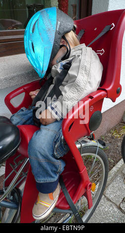 kleiner Junge aus einer Fahrradtour zurückgekehrt: zwei trinken, man schläft in den Kindersitz auf dem Fahrrad Stockfoto
