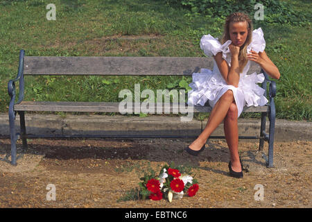 verlassene Braut sitzt auf einer Parkbank Stockfoto