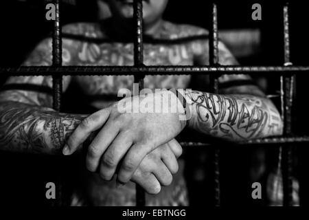 Eine Mara Salvatrucha Bandenmitglied ist hinter den Bars von Zellen in einem Abschiebelager in San Salvador, El Salvador, 20. Februar 2014 gesehen. Stockfoto