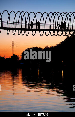 Menschen auf die Slinky Slinky Springs zu Ruhm zu überbrücken, Rehberger Bruecke bei Sonnenuntergang über Rhein-Herne-Kanal, Deutschland, Nordrhein-Westfalen, Ruhrgebiet, Oberhausen Stockfoto