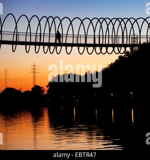 Biker auf der Slinky Slinky Springs zum Ruhm bei Sonnenuntergang Brücke über den Rhein-Herne-Kanal, Deutschland, Nordrhein-Westfalen, Ruhrgebiet, Oberhausen Stockfoto