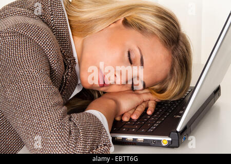 blonde junge Frau über ihren Laptop eingeschlafen Stockfoto