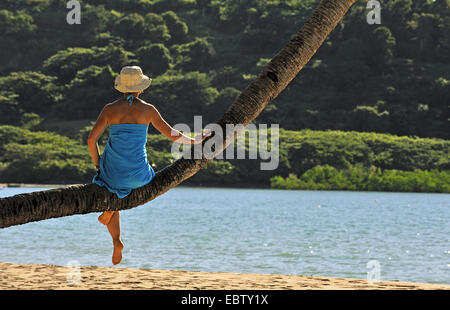 Frau sitzt auf Palme am Sandstrand, Madagaskar, Nosy werden Stockfoto