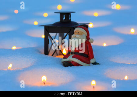 Santa Claus Figuren mit Laterne und viele Kerzenlicht im Schnee Stockfoto
