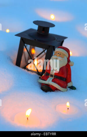 Santa Claus Figuren mit Laterne und Kerzenlicht im Schnee Stockfoto