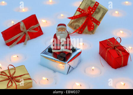 Santa Claus Figur mit Weihnachten gegenwärtigen Packs und Teelichtern im Schnee Stockfoto