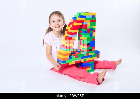 vier-jährigen Mädchen mit einer großen Zahl "4" aus Legosteinen gebaut Stockfoto