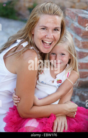 Mutter und Tochter umarmt und blicken in Richtung Kamera Stockfoto