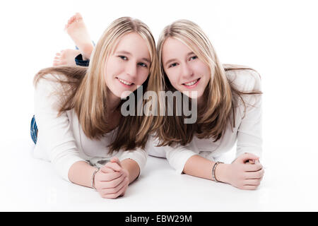 zwei junge twin Schwestern liegen nebeneinander lächelnd Stockfoto