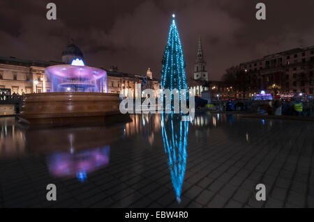 London, UK. 4. Dezember 2014. Die jährliche Weihnachtsbaum Beleuchtungszeremonie findet statt am Trafalgar Square.  Der Baum wird von der Stadt Oslo für die Menschen in London jährlich als Zeichen der Dankbarkeit für die Unterstützung Großbritanniens während des zweiten Weltkriegs gestiftet.  Im Bild: die Lichter von den neu beleuchteten Weihnachtsbaum spiegelt sich in den Brunnen. Bildnachweis: Stephen Chung/Alamy Live-Nachrichten Stockfoto