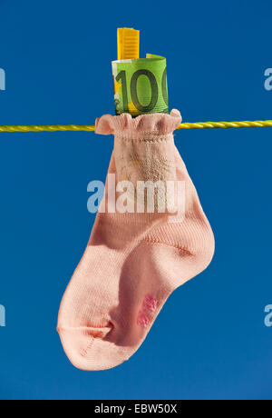 Baby-Socke mit Euro-Banknoten auf der Wäscheleine Stockfoto